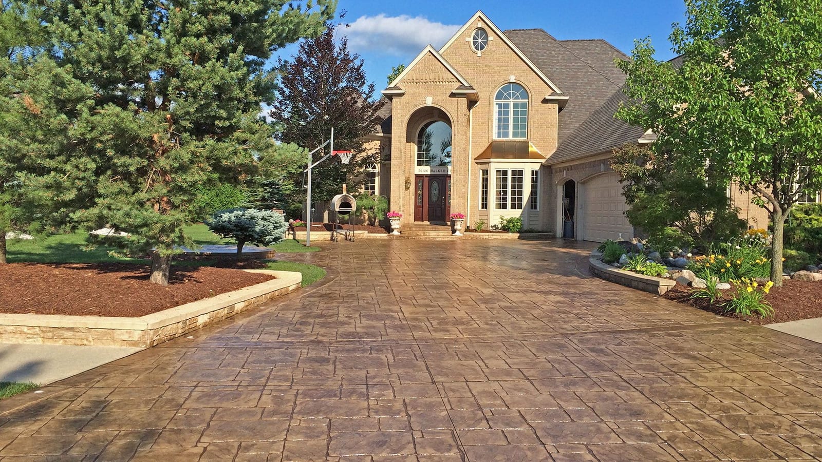 Stamped concrete driveway with a gloss sealer in front of a brick estate home in Southwestern Ontario